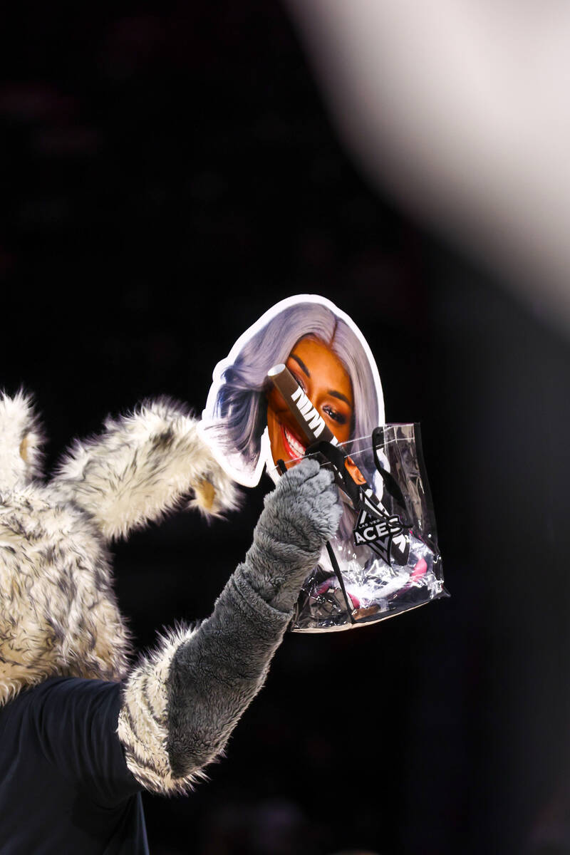 BUCKET$, the Aces mascot, holds up a swap bag to give out to a fan during a break in the action ...