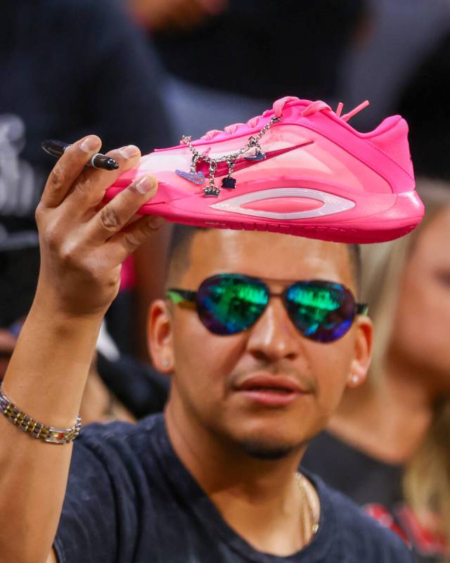 A fan holds up a decked-out A’ja Wilson A’One Nike shoe, trying to get it signed ...