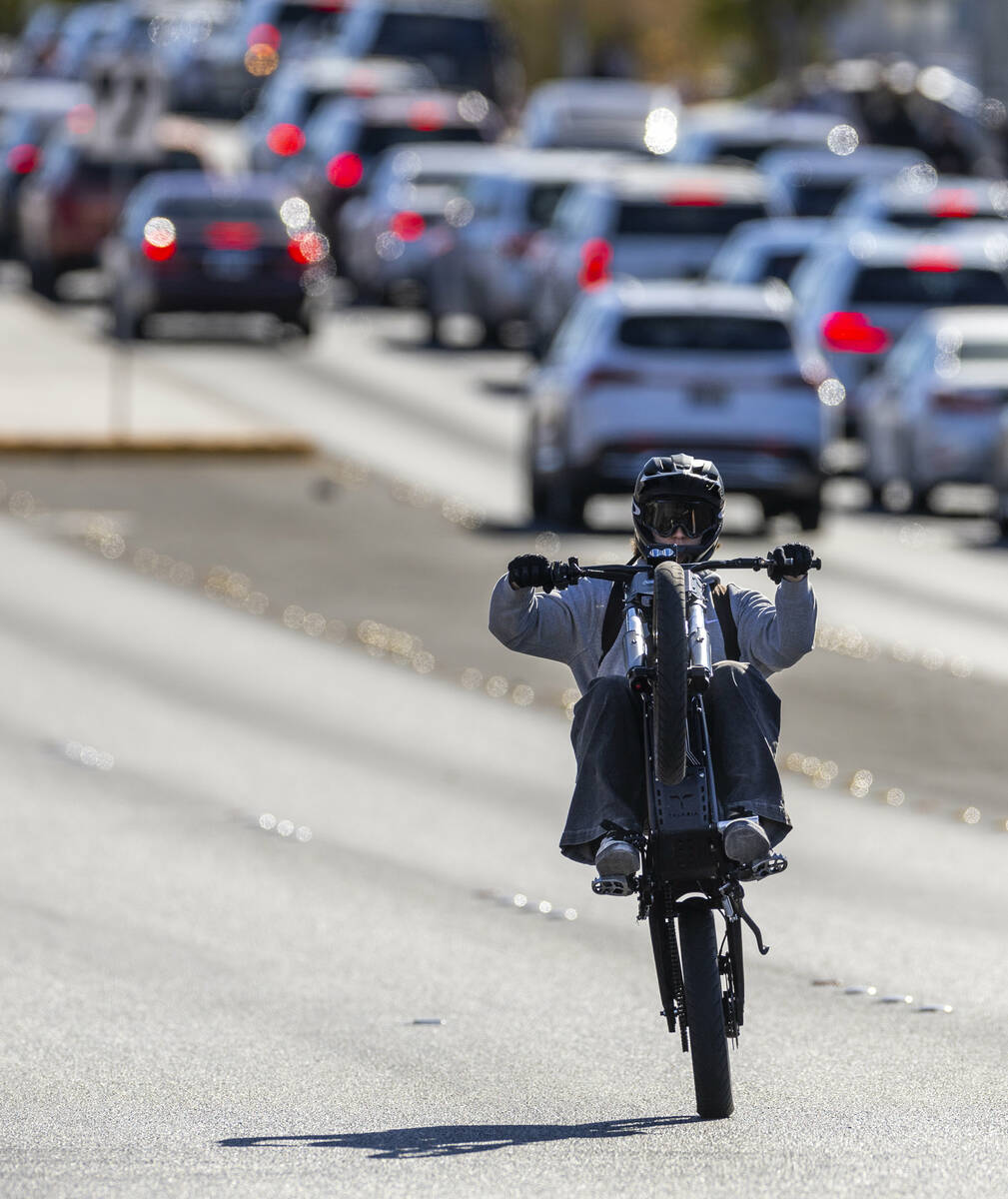 A student riding an e-dirt bike pop a wheelie along Coronado Center Drive from Coronado High Sc ...