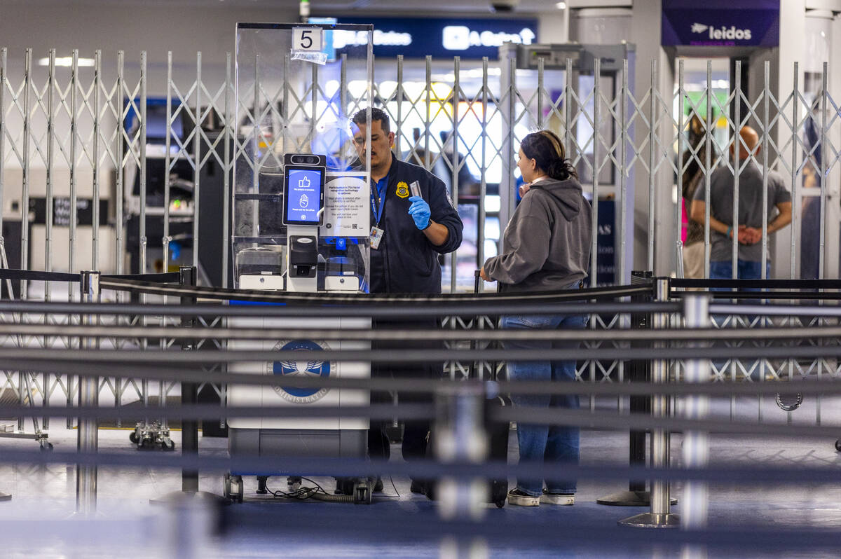 A traveler has her identification verified at the TSA security checkpoint in Terminal One as th ...