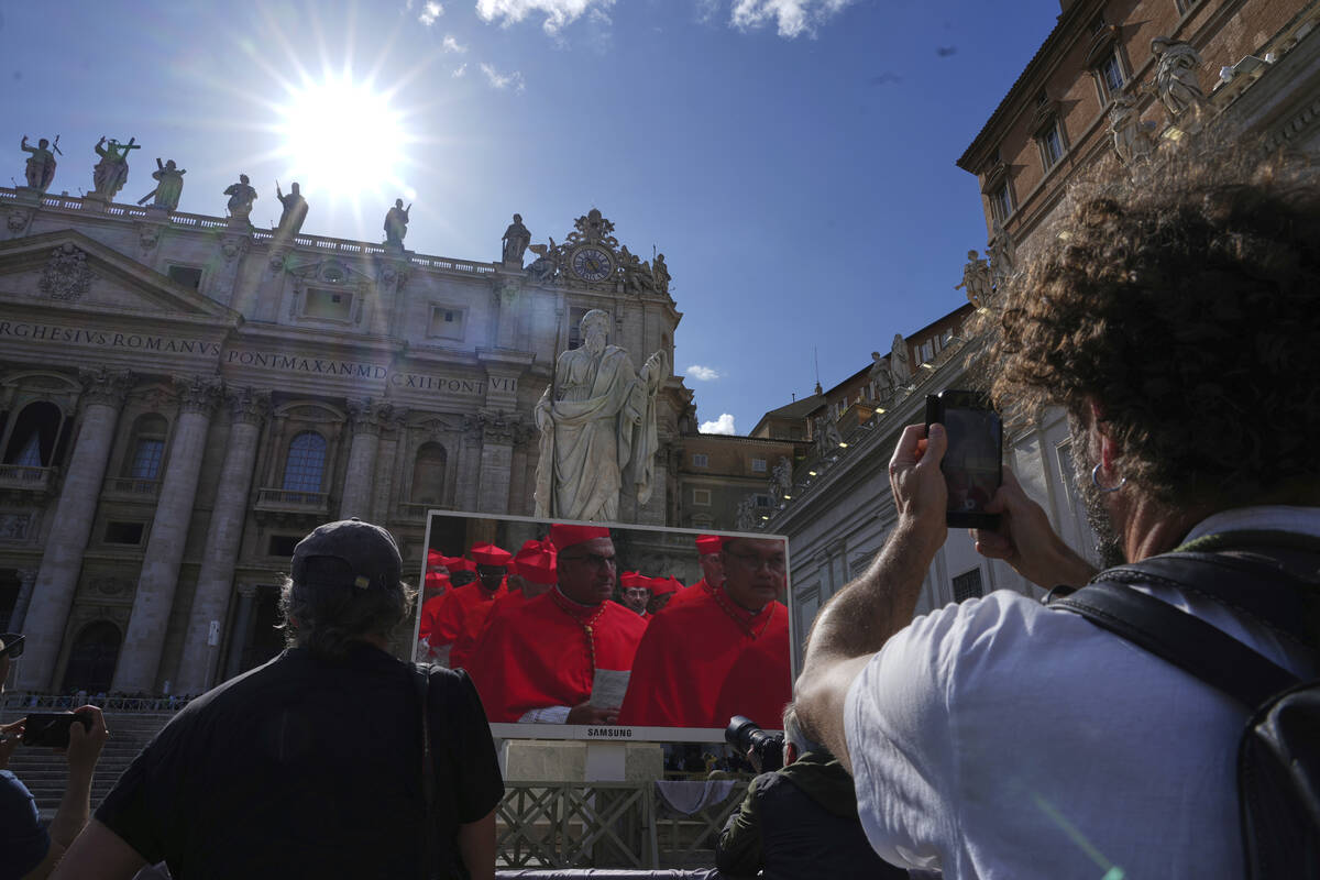 Faithful watch a giant screen showing images of cardinals entering the conclave, in St. Peter's ...
