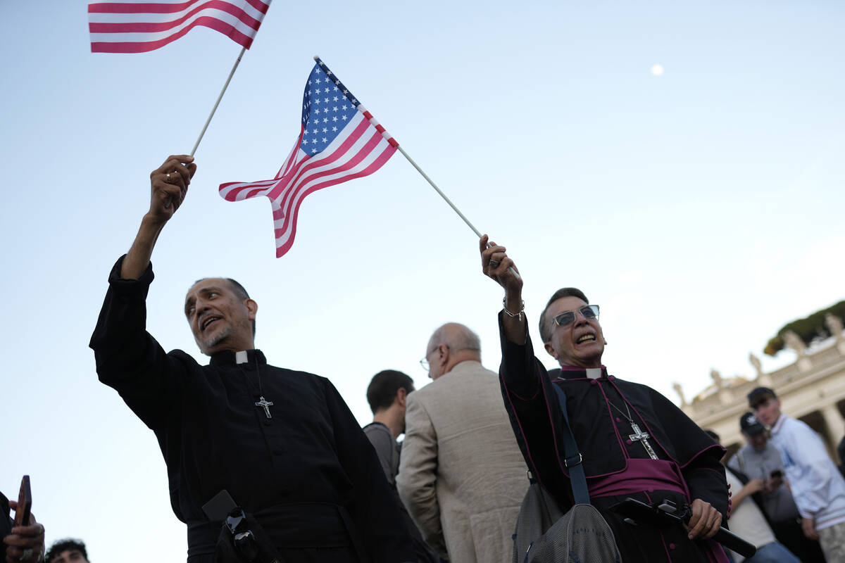 Clerics wave US flags during the speech of the newly elected Pope Leo XIV at the Vatican, Thurs ...