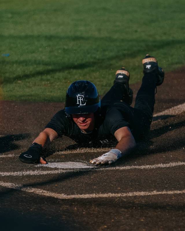 Faith Lutheran’s Nate Keyes (9) slides into home plate, earning a run for the Crusaders ...