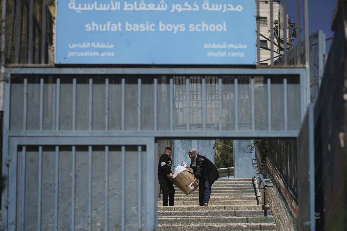 A student and a teacher carry study material at UNRWA Girls School run by the U.N. agency for P ...