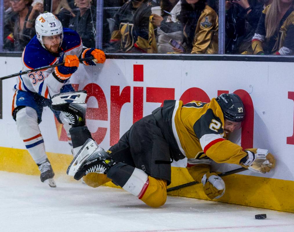 Golden Knights defenseman Shea Theodore (27) smashes into the boards after battling with Edmont ...