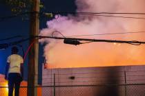 A person watches as a fire burns near West Twain Avenue and South Highland Drive on Thursday, M ...