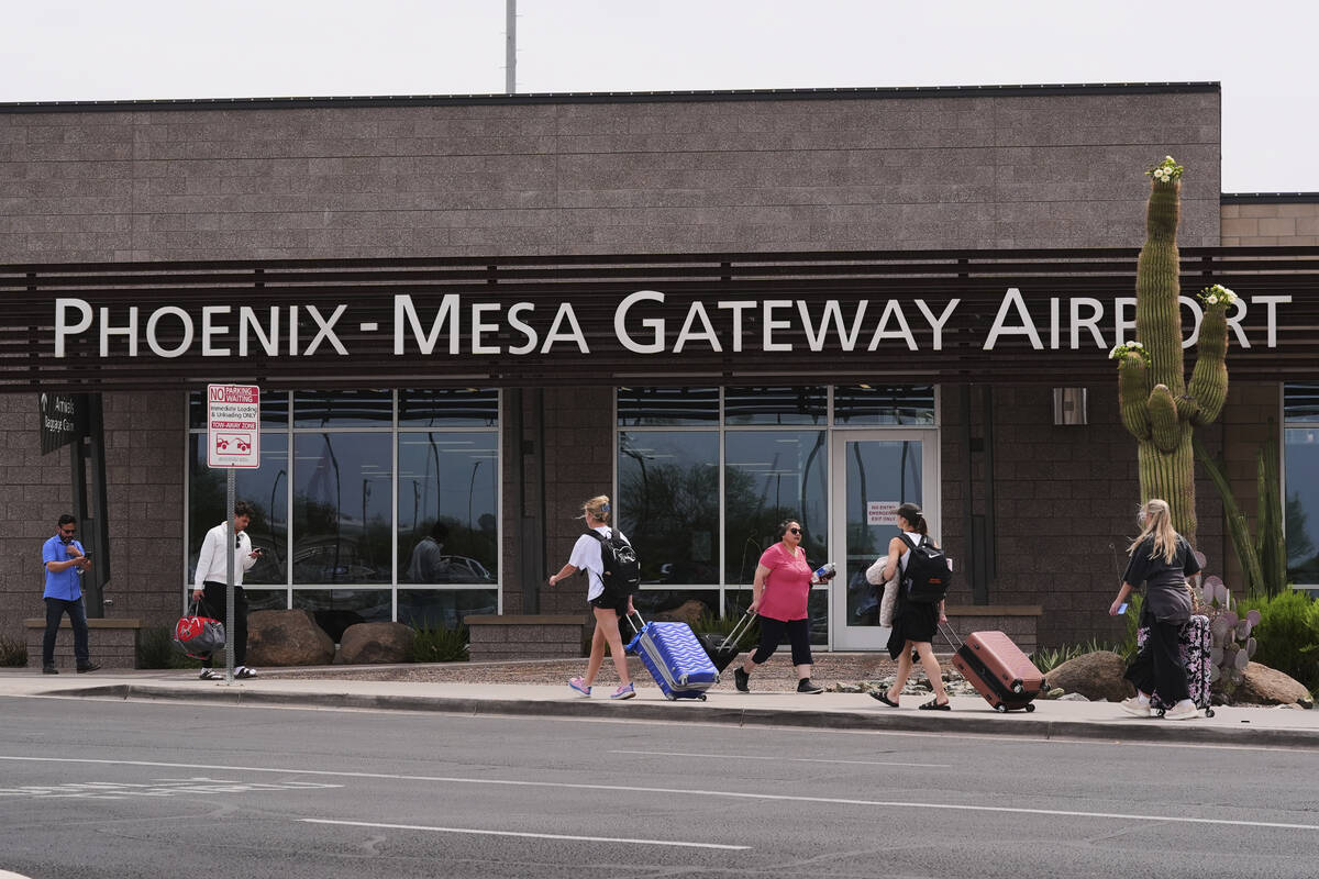 Passengers walk in front of Mesa Gateway Airport, where Avelo Airlines started making deportati ...