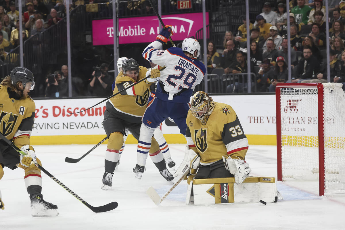 Golden Knights goaltender Adin Hill (33) deflects the puck as Golden Knights defenseman Zach Wh ...