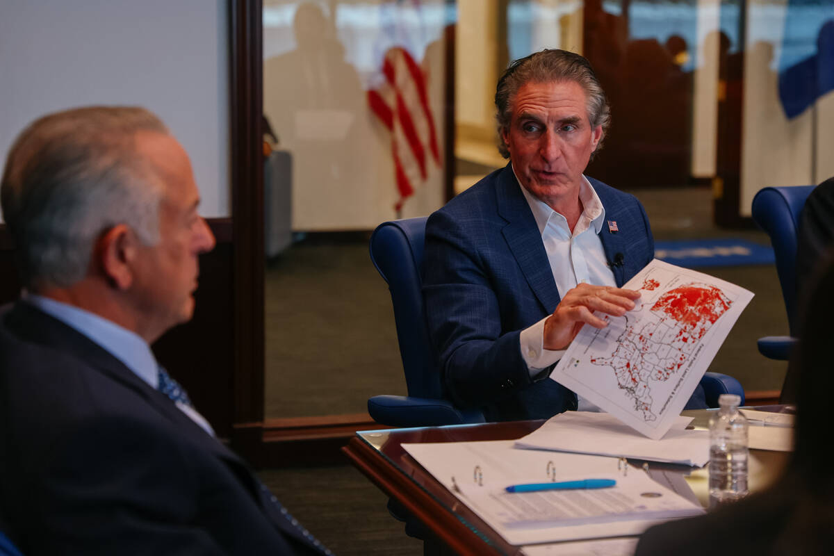 Interior Secretary Doug Burgum, right, holds up a map showing government-owned property to Gov. ...