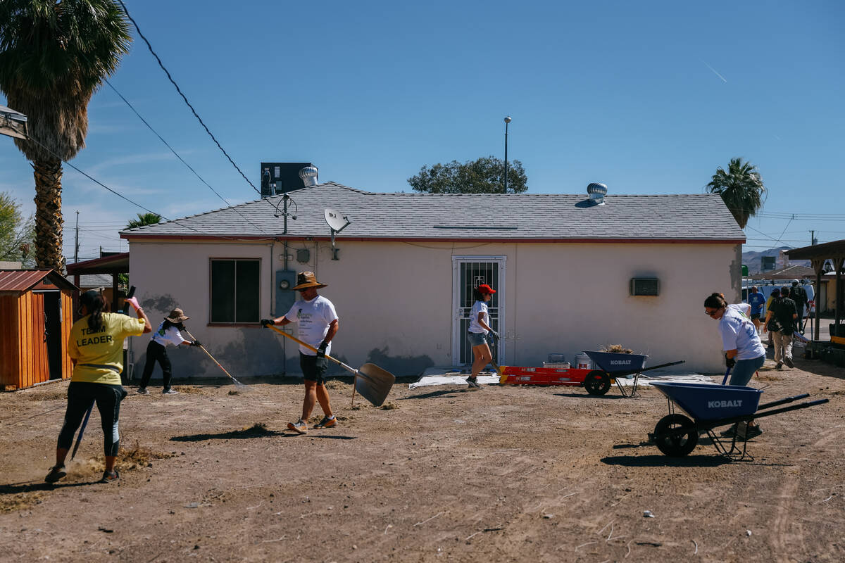 Realtors clean up debris from the backyard of a home while volunteering with Las Vegas REALTORS ...