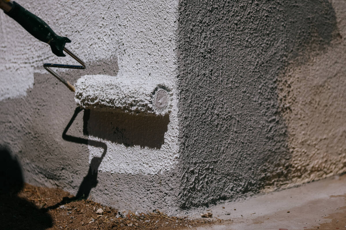 A volunteer applies a fresh coat of white paint to a home on Friday, May 16, 2025 in Henderson. ...
