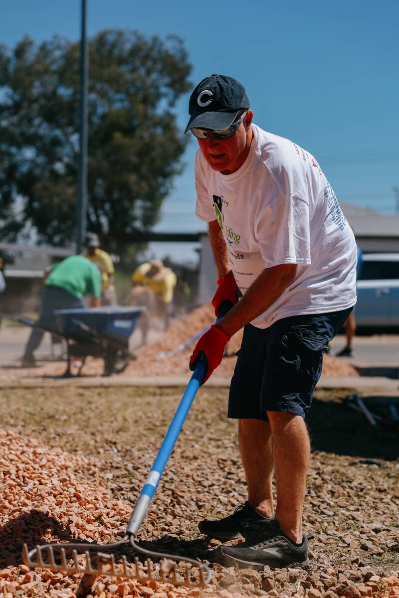 Realtor Tony Romano spreads out new rock over the front yard as he volunteers with the Las Vega ...