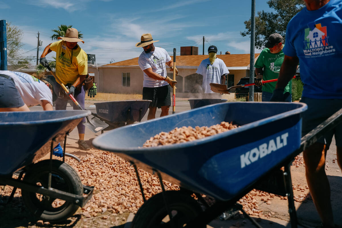 Volunteers with Las Vegas REALTORS and Rebuilding Together Southern Nevada shovel new rocks int ...