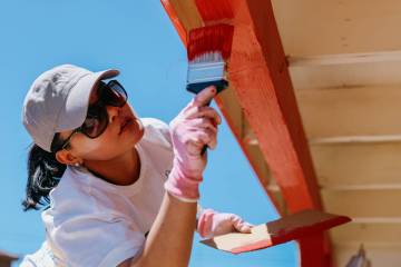 Realtor Peach Freeman paints the eaves of a home as she volunteers with Las Vegas REALTORS and ...