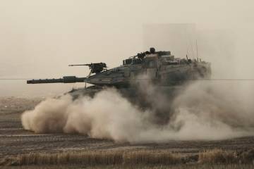 An Israeli tank moves in a staging area in southern Israel, near the border with Gaza, Friday, ...