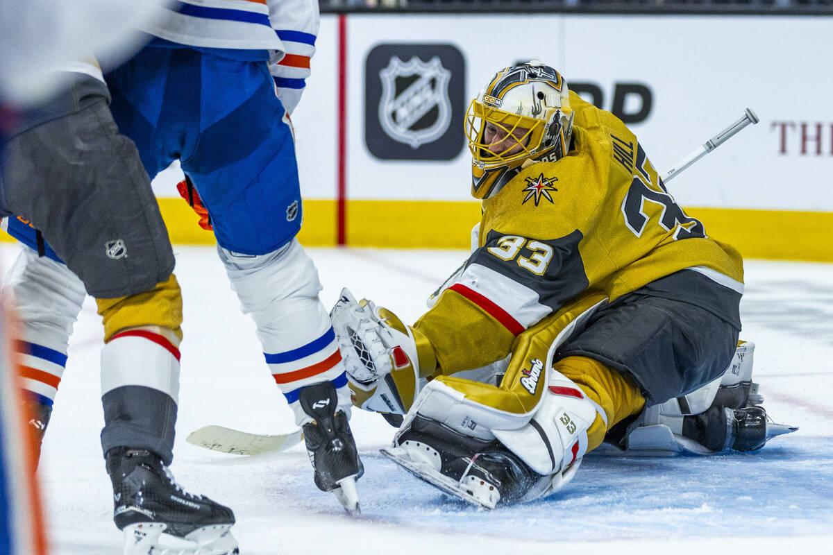 Golden Knights goaltender Adin Hill (33) grabs a puck as he defends the net from a shot by Edmo ...