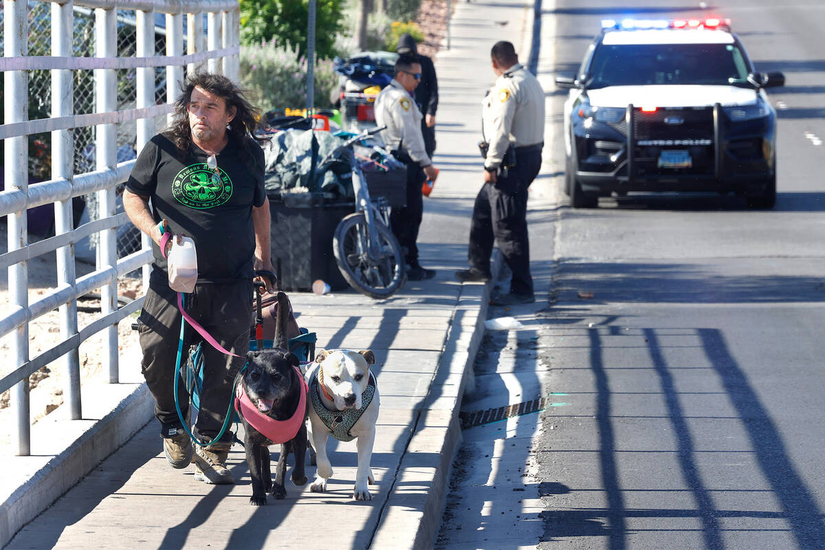 Scott Branner, who is homeless, and his dogs walk along Cambridge Street as contract workers cl ...