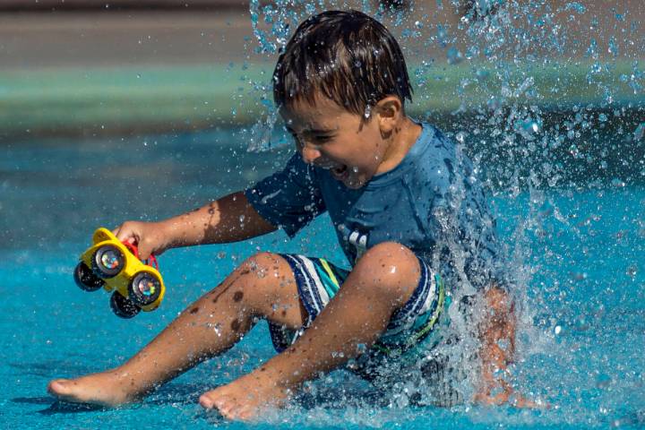 Leo Reyes, 3, sits on a water fountain as he stays cool on the splash pad at The Paseos Park in ...