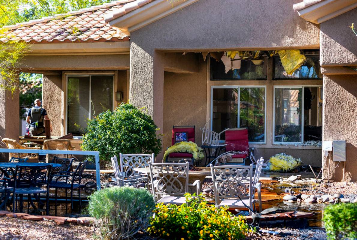 An investigator walks about the rear of a house fire on Clarion Lane with 14 Las Vegas Fire Dep ...
