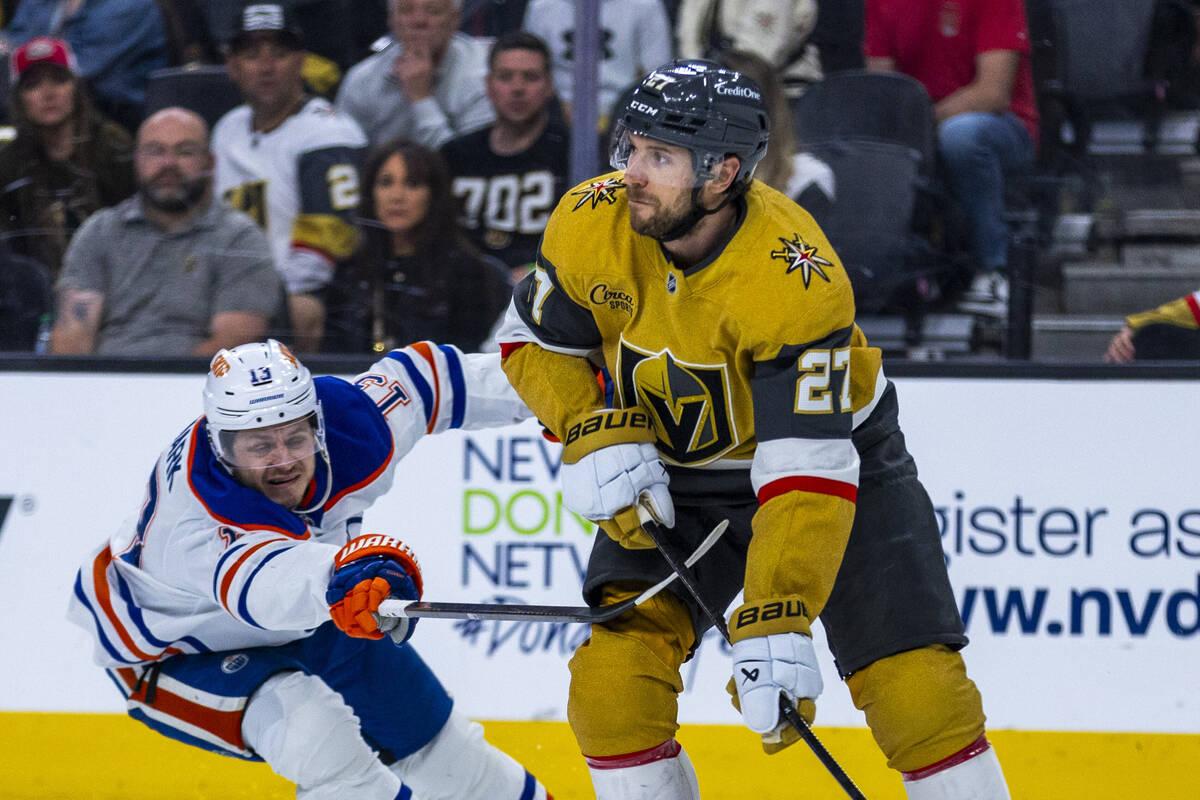Golden Knights defenseman Shea Theodore (27) looks to pass as Edmonton Oilers center Mattias Ja ...