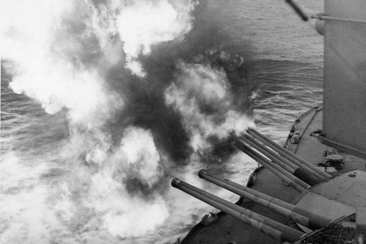 Mushrooms of smoke and flame billow out from the giant USS Nevada as the battleship provides ar ...