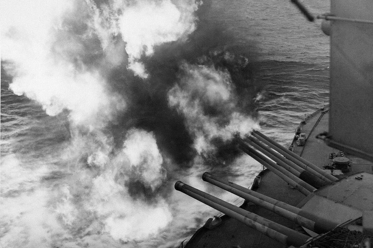 Mushrooms of smoke and flame billow out from the giant USS Nevada as the battleship provides ar ...