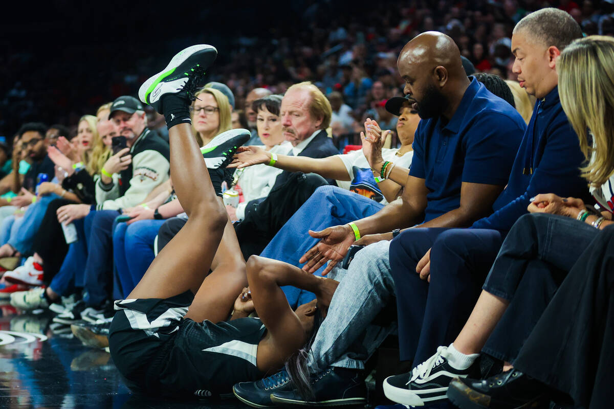 Aces guard Jackie Young falls into the crowd during a WNBA basketball game between the Aces and ...