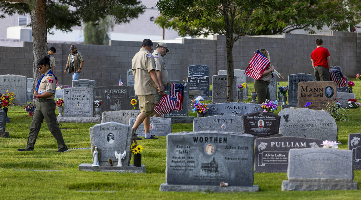 Scouting America troops assist with placing American flags at the gravesites of veterans at the ...