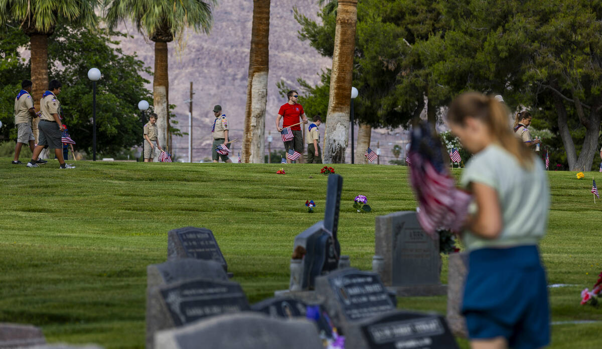 Scouting America troops assist with placing American flags at the gravesites of veterans at the ...
