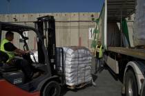 Workers unload cargo from a truck carrying humanitarian aid for the Gaza Strip at the offload a ...