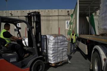 Workers unload cargo from a truck carrying humanitarian aid for the Gaza Strip at the offload a ...