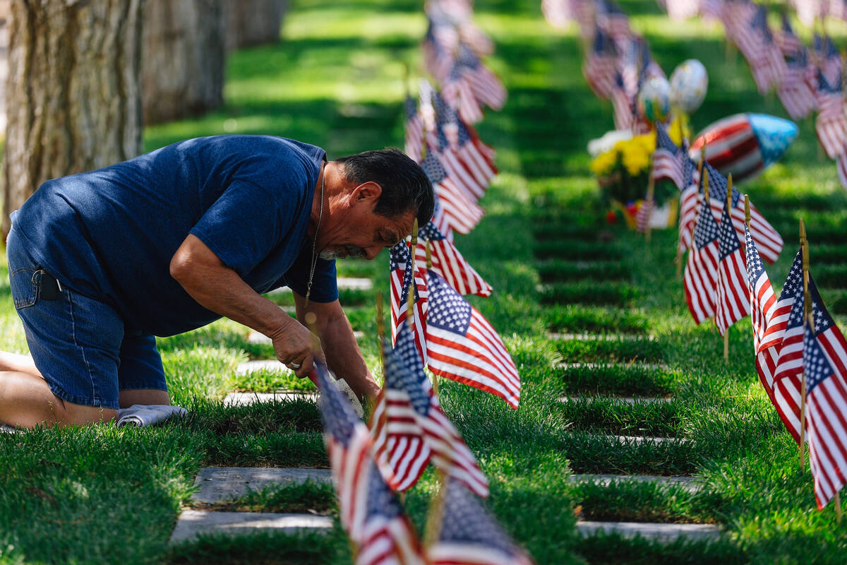 Tommy Rheault makes space to place flowers at a grave at the Southern Nevada Veterans Memorial ...