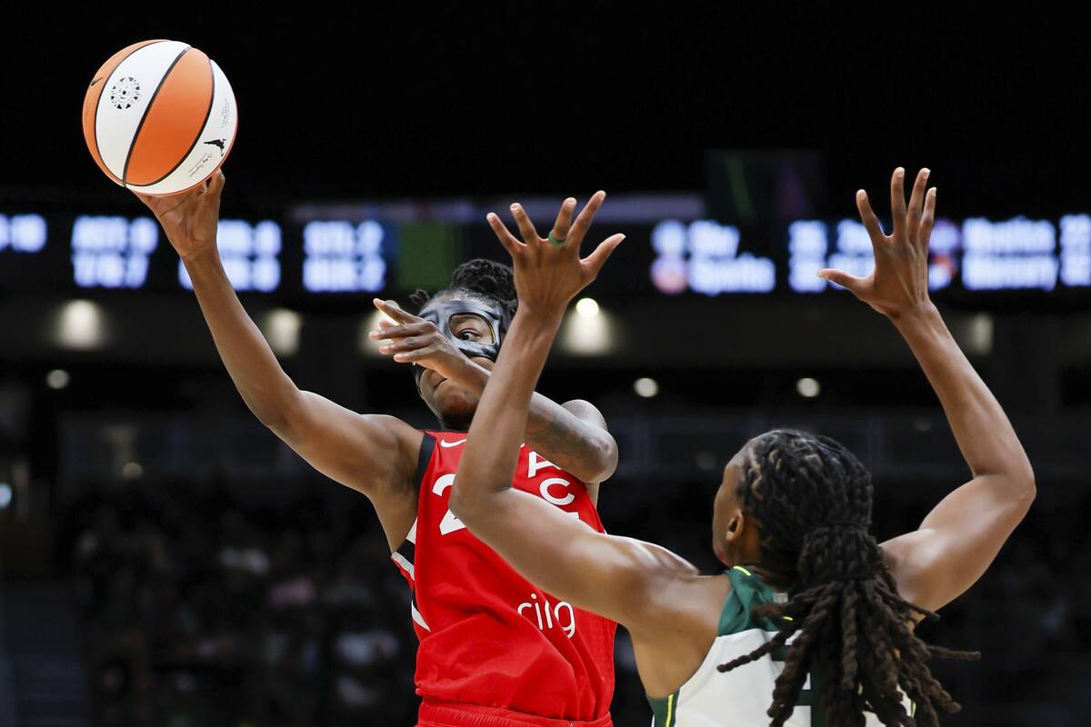 A masked Las Vegas Aces guard Jewell Loyd passes the ball as Seattle Storm forward Nneka Ogwumi ...