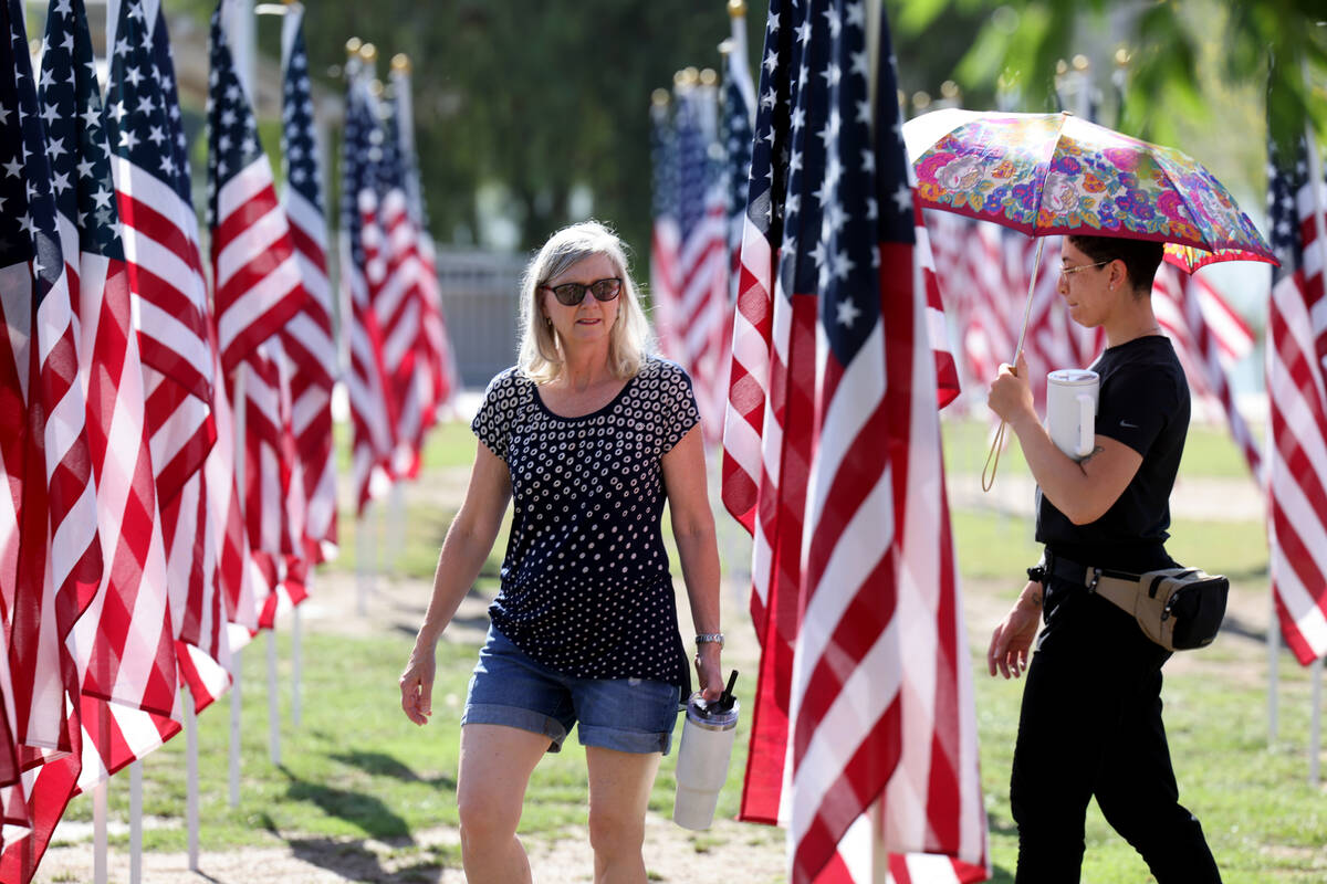 Andi Graham, left, and Eden Sigler, both of Henderson, walk among flags before the Field of Hon ...