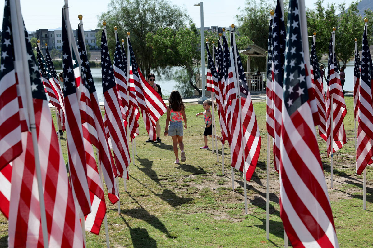 Families walk among flags before the Field of Honor ceremony at Cornerstone Park in Henderson o ...