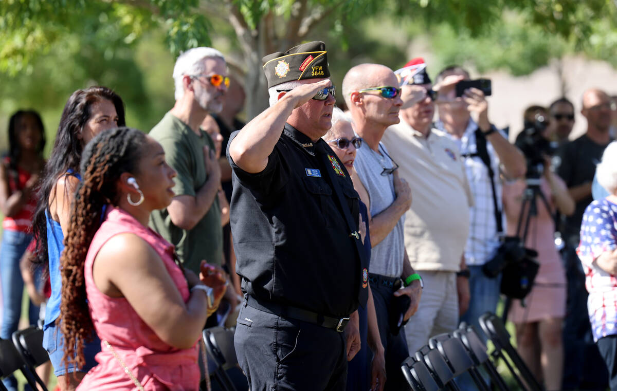 Audience members stand and salute as the colors are presented during the Field of Honor ceremon ...