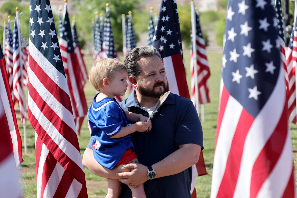Brandon Phillips and his son Royal Phillips, 2, listen during the Field of Honor ceremony at Co ...