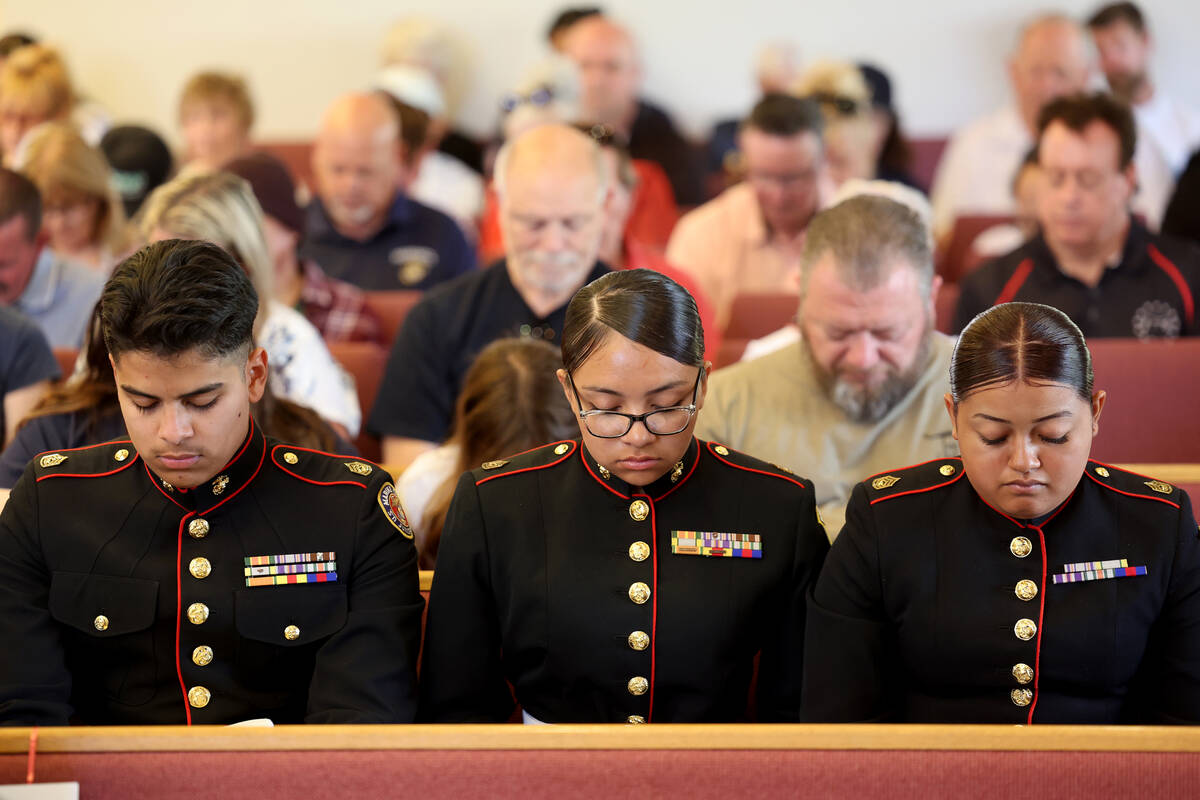 Audience members, including members of the Desert Pines Marine Corps JROTC, pray during the Mem ...