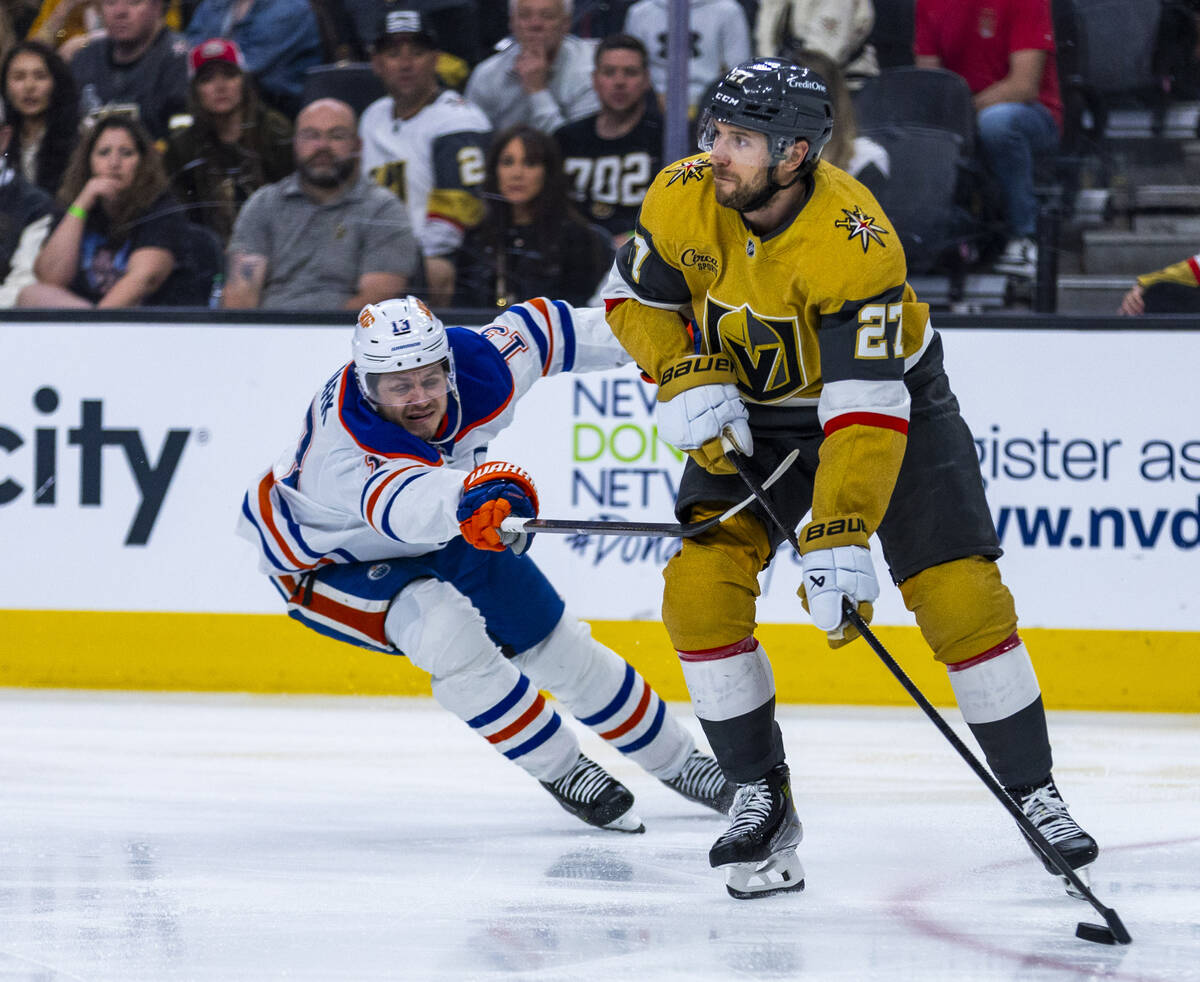 Golden Knights defenseman Shea Theodore (27) looks to pass as Edmonton Oilers center Mattias Ja ...