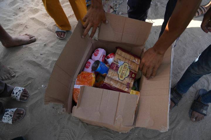 Palestinians open a box containing food and humanitarian aid packages delivered by the Gaza Hum ...