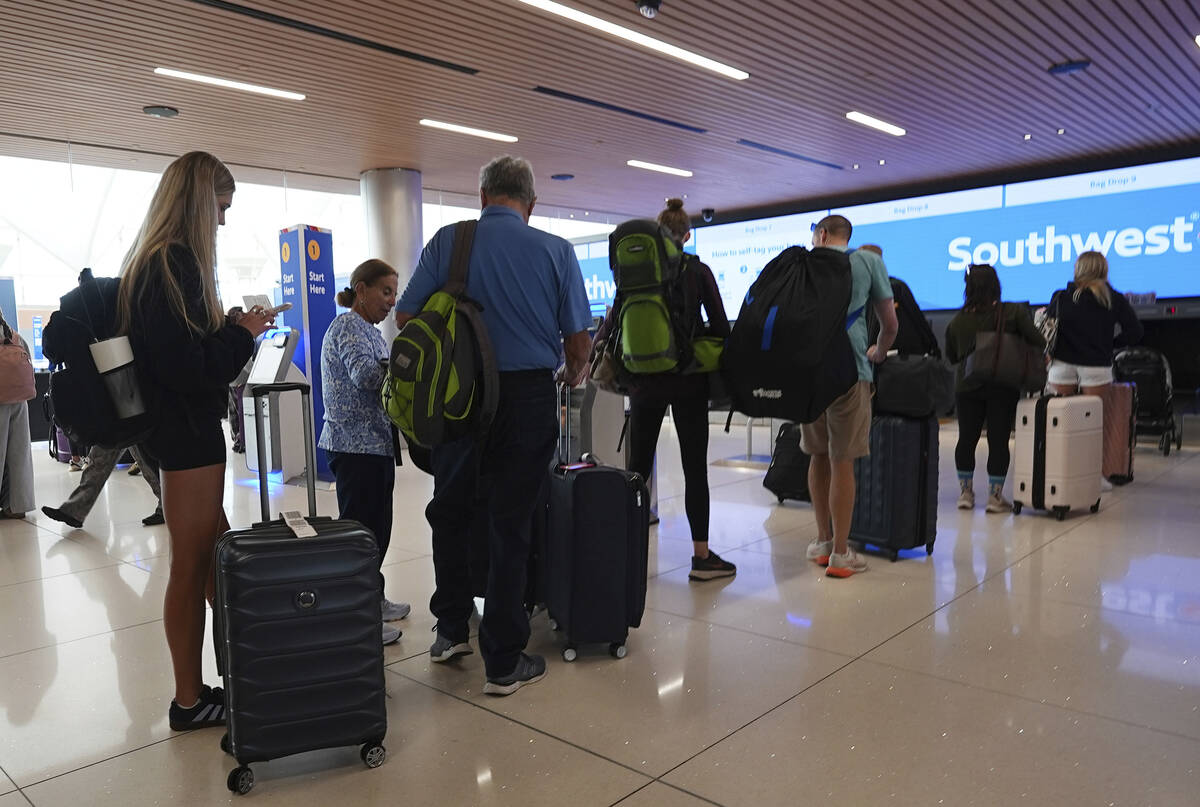 Travelers queue up at the check-in counters for their flights on Southwest Airlines in the main ...