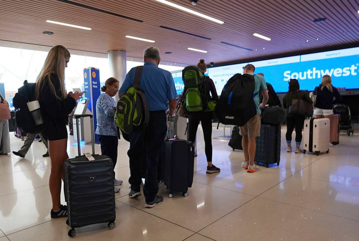 Travelers queue up at the check-in counters for their flights on Southwest Airlines in the main ...