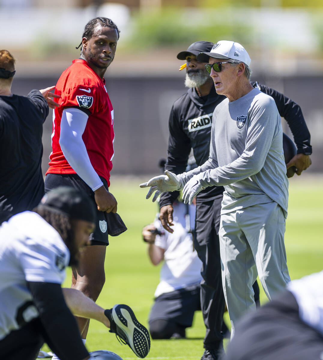 Raiders quarterback Geno Smith (7) chats with head coach Pete Carroll and others as the team wa ...