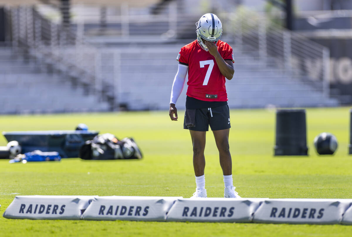 Raiders quarterback Geno Smith (7) takes a quick break as the sun beats down on him and teammat ...