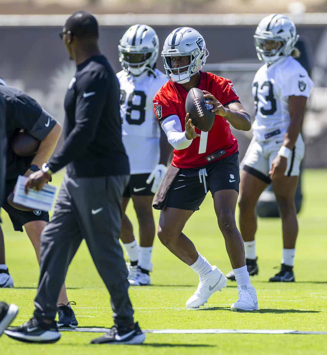 Raiders quarterback Geno Smith (7) takes a snap while looking to lateral during OTA's at the In ...