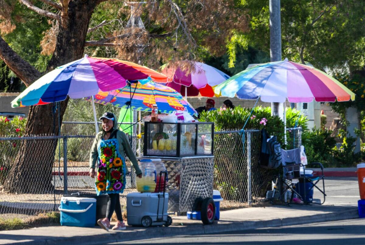 Street vendors keep cool under colorful umbrellas while working about East Tonopah Avenue on Th ...
