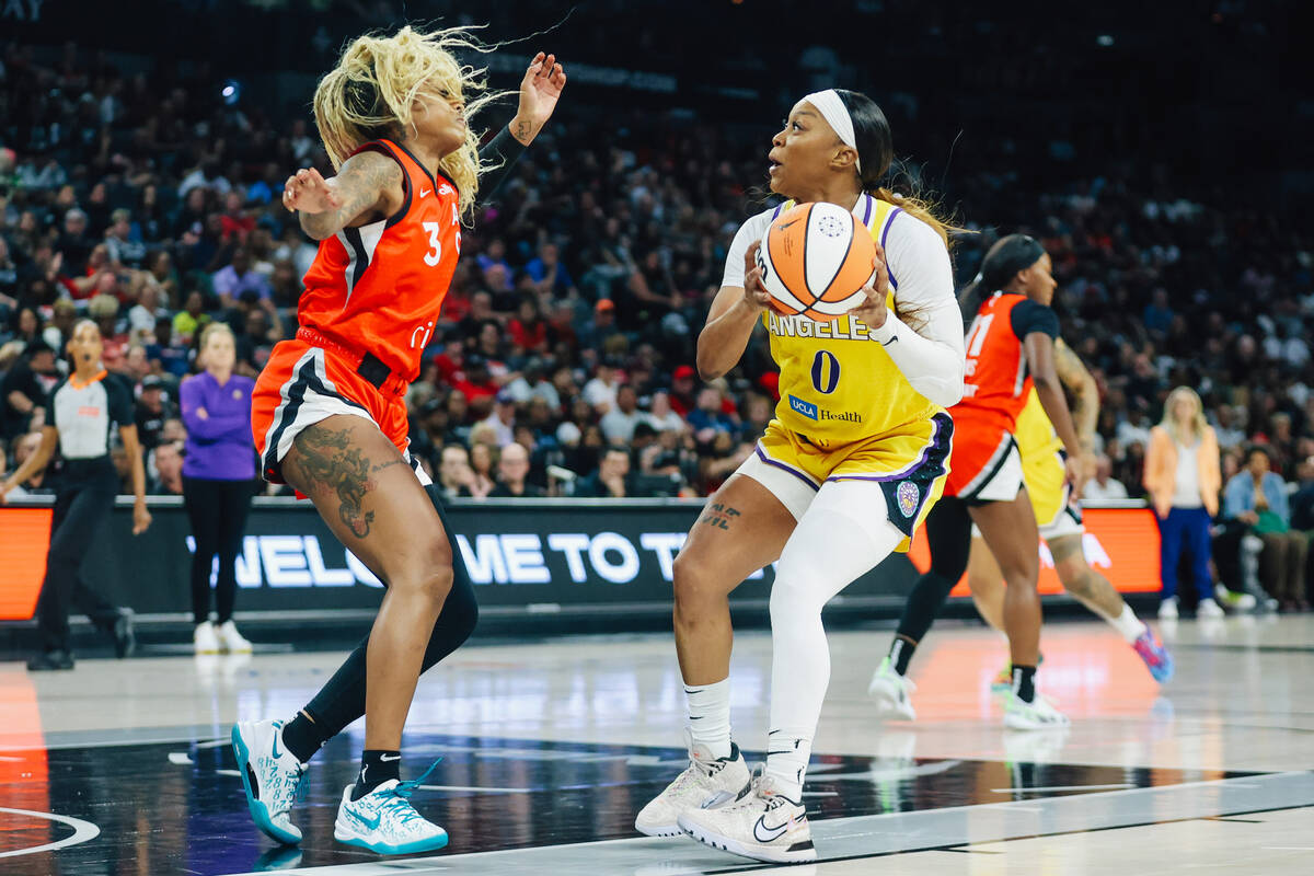 Los Angeles Sparks guard Odyssey Sims (0) eyes the basket as Aces guard Tiffany Mitchell (3) de ...