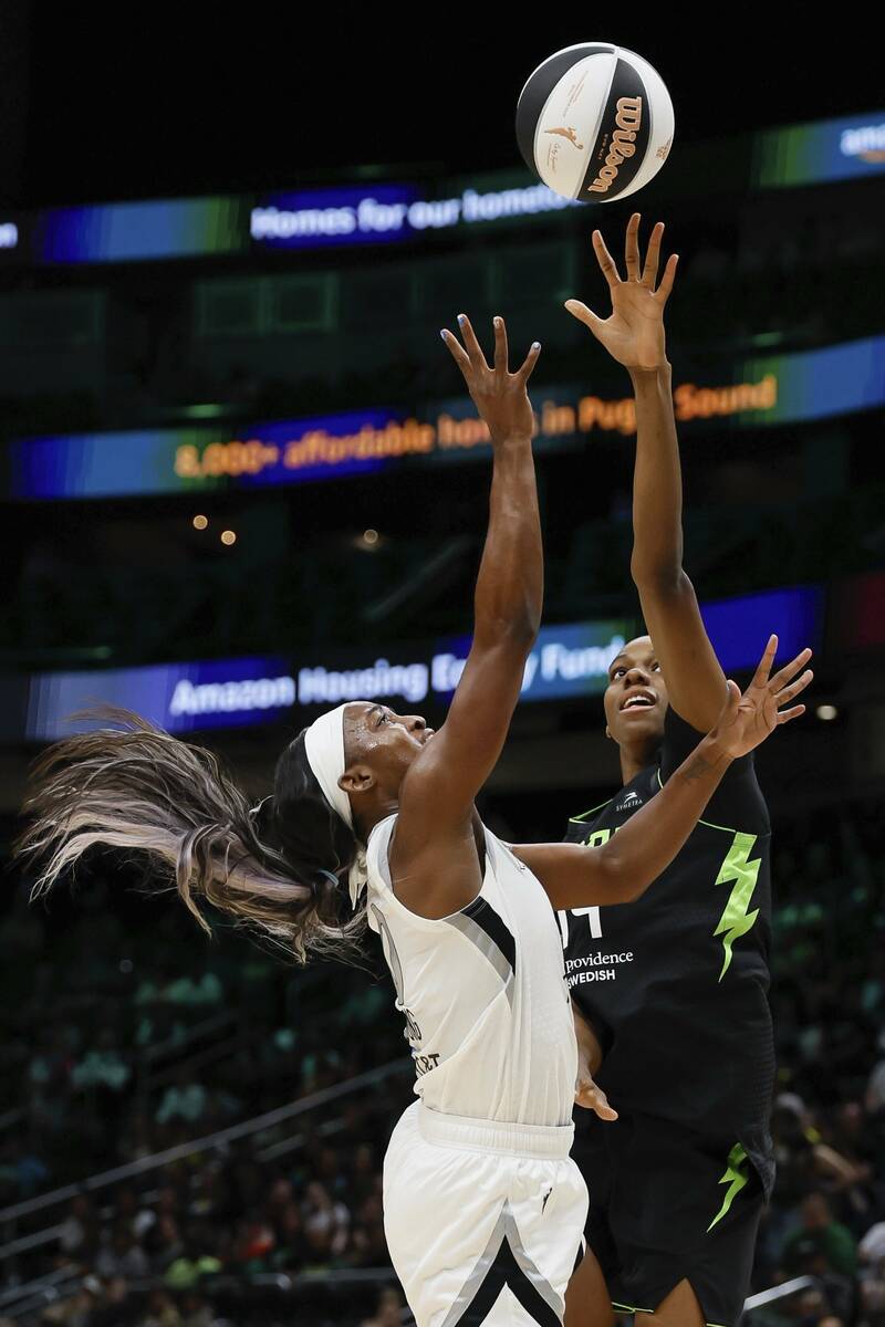 Las Vegas Aces guard Jackie Young, left, shoots against Seattle Storm center Dominique Malonga, ...