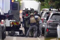 Law enforcement officials dress in protective gear to investigate after an attack on the Pearl ...