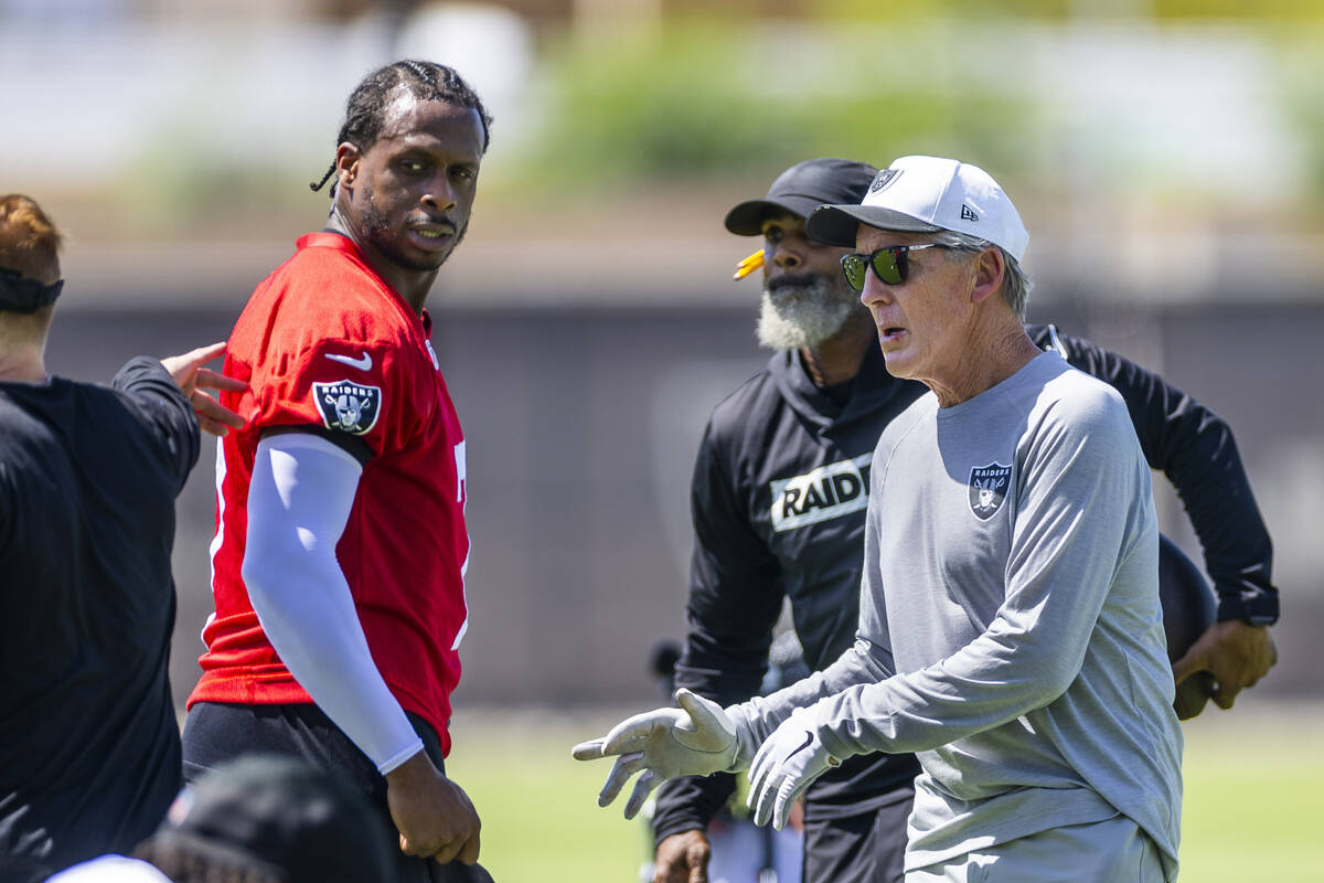 Raiders quarterback Geno Smith (7) chats with head coach Pete Carroll and others as the team wa ...